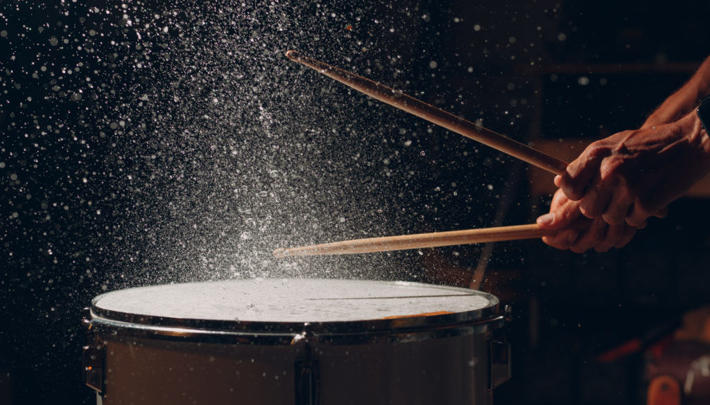 Drum sticks drumming beat rhythm on drum surface with splash water drops