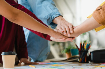 asian-businessmen-businesswomen-meeting-brainstorming-putting-hands-up-new-startup-giving-strength-motivation-working-together-modern-creative-office-coworker-teamwork-concept