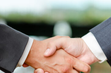 Corporate Businessmen Handshake Indoors.Two People Professionally Well Dressed Gesturing Togetherness.Working Colleague Partners Sign Deal In Agreement To Contract