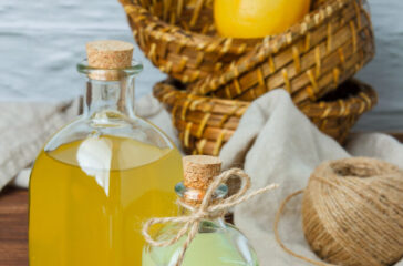 Set of on piece of white cloth, lemon leaves and lemon and juice in a basket on a wooden background. high angle view. space for text