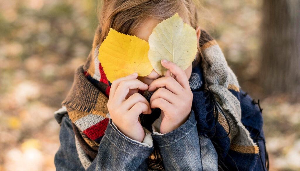 medium-shot-kid-covering-face-with-leaves