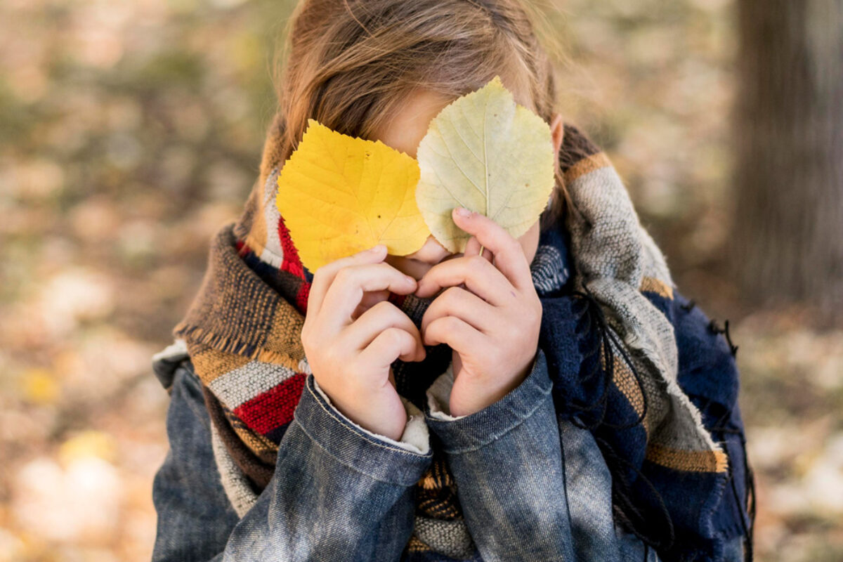 medium-shot-kid-covering-face-with-leaves