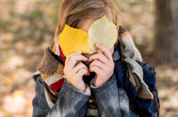 medium-shot-kid-covering-face-with-leaves